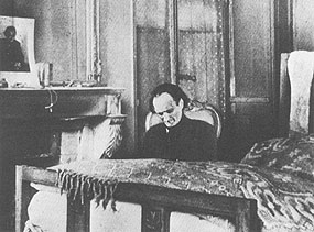 Antonin Artaud sitzend in einem Klinikzimmer.